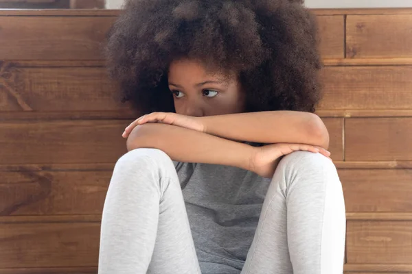 Beleidigte kleine afrikanisch-amerikanische Mädchen sitzt auf dem Boden. — Stockfoto