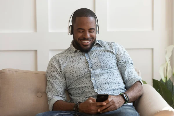 Yakışıklı genç afro-amerikan adam kablosuz bluetooth kulaklık giyiyor.