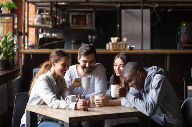 Kafede eğlenen, akıllı telefon ekranına bakan farklı arkadaşlar