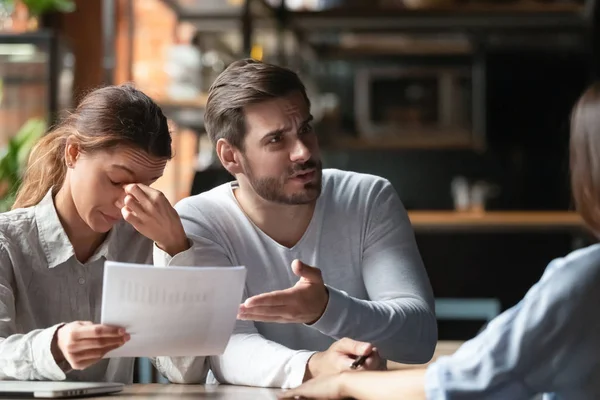 Jeune couple en colère se plaignant, mauvais termes du contrat, se disputant avec le gestionnaire — Photo