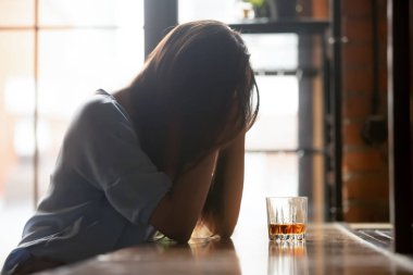 Yalnız mutsuz kadın alkol bardak ile tek başına oturan