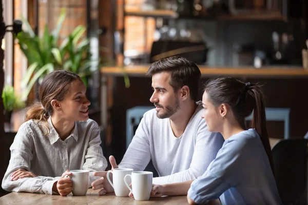 Diverse friends chatting, drinking coffee, sitting together in cafe — Stock Photo, Image