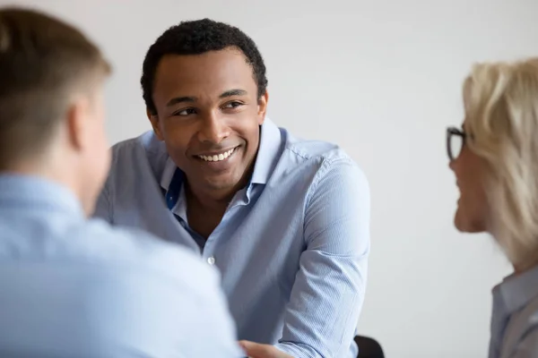 Sonriente hombre de negocios negro hablar con colegas en la reunión de la oficina — Foto de Stock