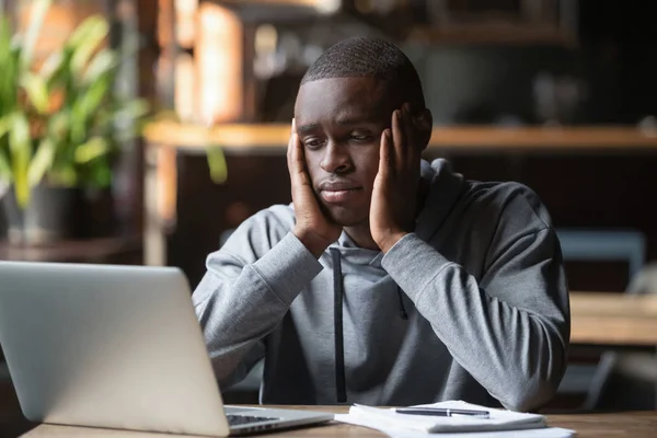 Cansado hombre afroamericano trabajando en la computadora portátil en el café — Foto de Stock