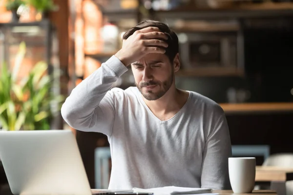 Upprörd man arbetar i Café, lider av huvudvärk, röra pannan — Stockfoto