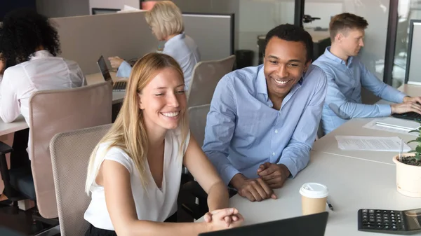 Usmívající se různorodé kolegy smějí sledovat video na přenosném počítači v kanceláři — Stock fotografie