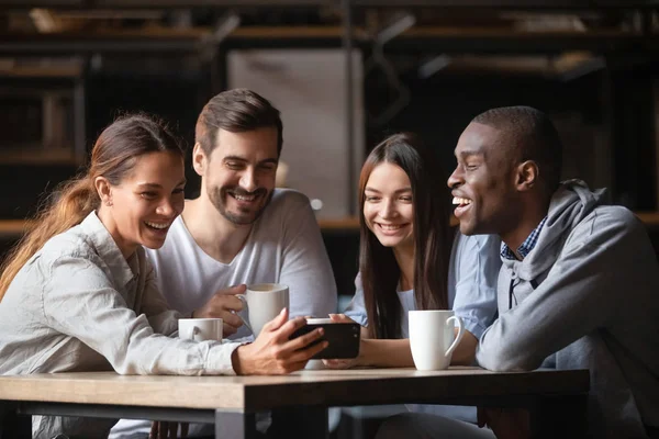 Glücklich diverse Freunde sehen lustige Video am Telefon in Café zusammen — Stockfoto