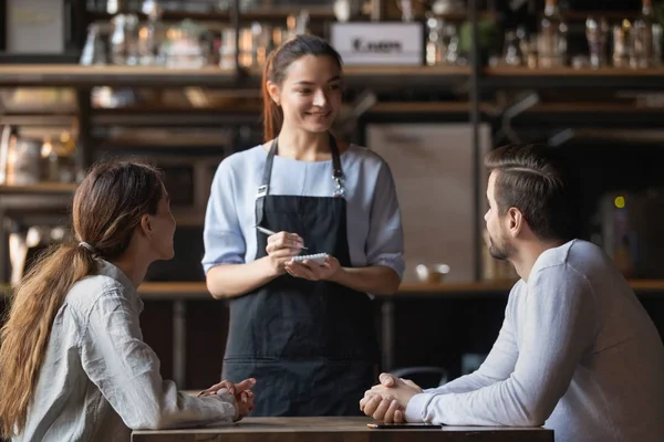 Couple making order in cafe, smiling waitress writing in notepad — Stock Photo, Image