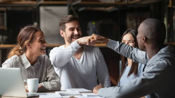 Diverse friends fists bumping, celebrate successful teamwork results in cafe — Stock Photo, Image