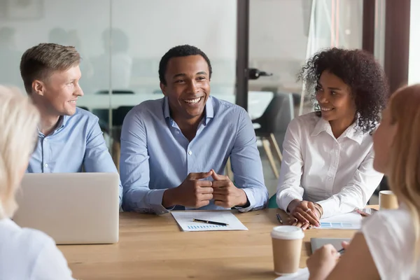 Glimlachende multiraciale collega's onderhandelen over samenwerking tijdens vergadering — Stockfoto