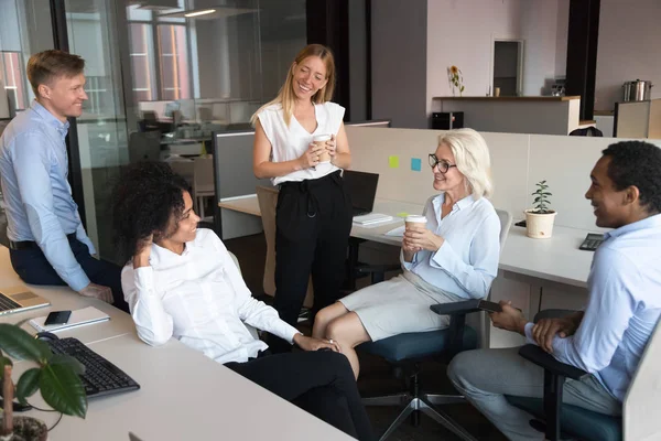 Uśmiechnięci pracownicy rozmawiają na nieformalnym spotkaniu w otwartej przestrzeni — Zdjęcie stockowe