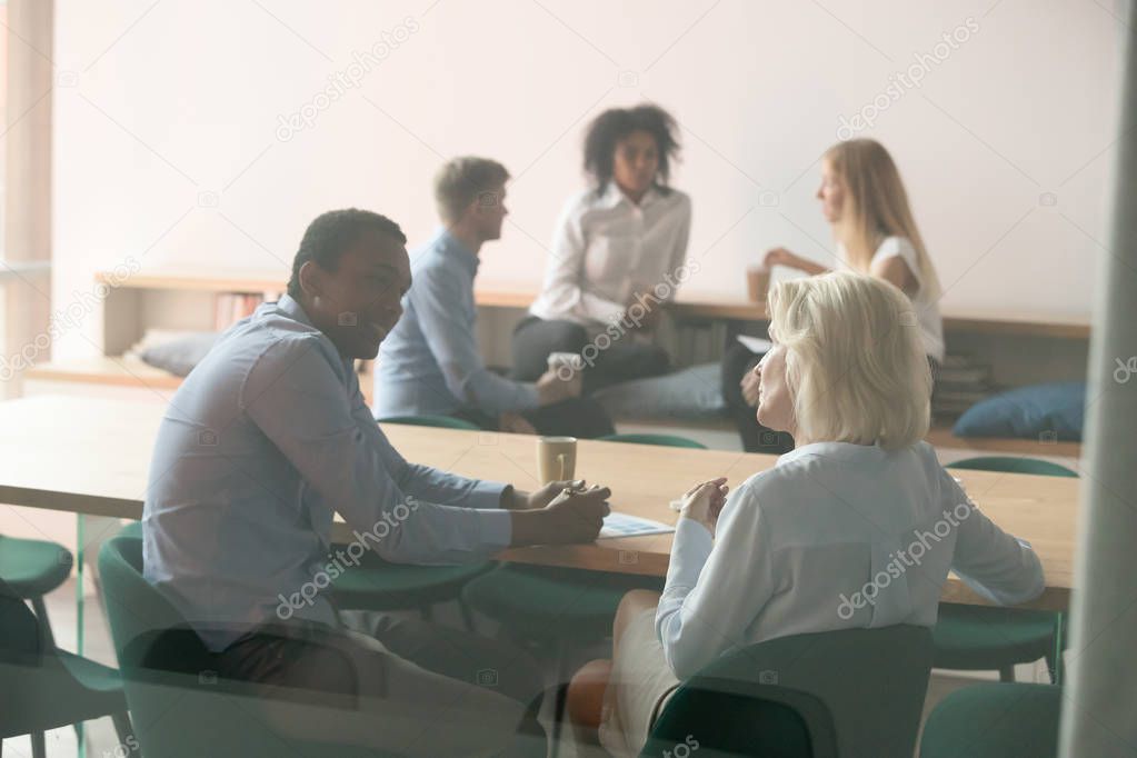 Diverse employee talk discussing ideas at break in boardroom