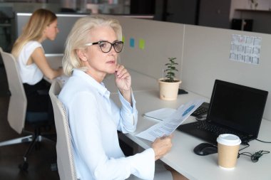 Ofis işlerinden dikkatinin dağıldığını düşünen pensive orta yaşlı kadın