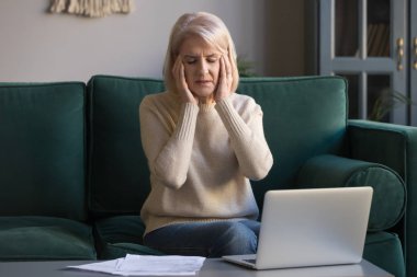 Hasta olgun kadın dizüstü bilgisayarda overworked baş ağrısı muzdarip