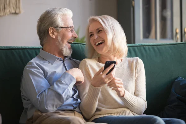 Familia feliz jubilados riendo usando smartphone en casa . —  Fotos de Stock