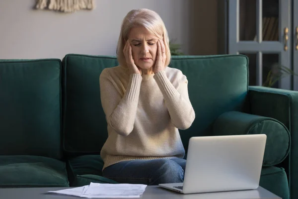 Hasta olgun kadın dizüstü bilgisayarda overworked baş ağrısı muzdarip — Stok fotoğraf