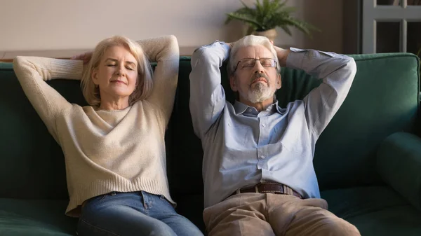 Tired senior spouses relax on cozy couch at home — Stock Photo, Image