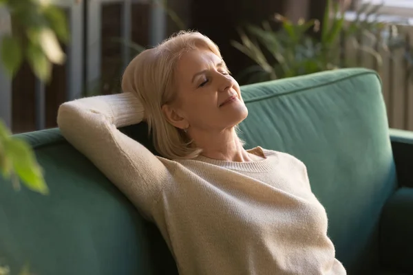 Erschöpfte reife Frau entspannt sich auf Couch mit geschlossenen Augen — Stockfoto