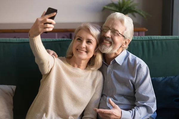 Moderna sonriente pareja de ancianos tomar selfie en el teléfono inteligente —  Fotos de Stock