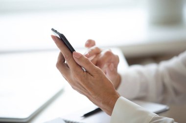 İşyerinde internet kullanarak cep telefonu tutan kadının yakın çekim