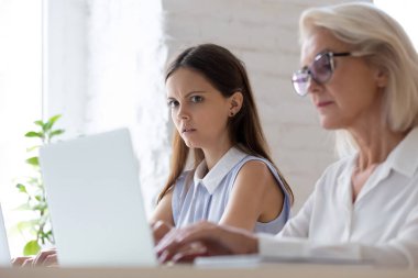 Shocked female employee look amazed peeping at coworker laptop clipart