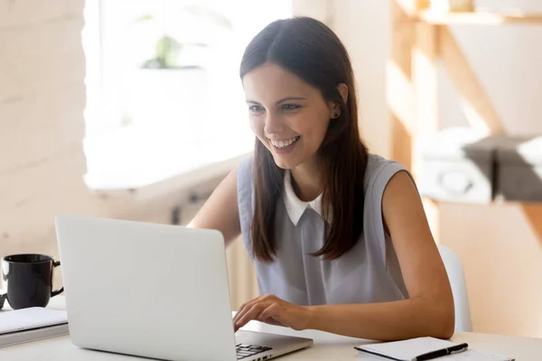 Glückliche junge Frau, die zu Hause am Laptop arbeitet — Stockfoto