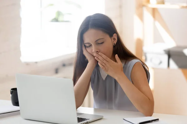 Empleada cansada bosteza sintiéndose somnolienta en el lugar de trabajo — Foto de Stock