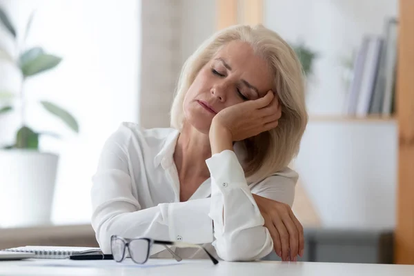 La mujer de negocios mayor agotada se queda dormida en el lugar de trabajo — Foto de Stock
