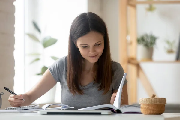Молодая девушка студентка занята учебой с книгой на дому — стоковое фото