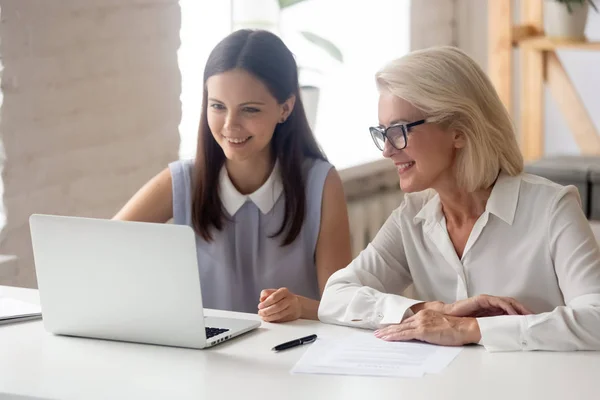 Las empleadas sonrientes trabajan juntas en la computadora portátil en la oficina — Foto de Stock