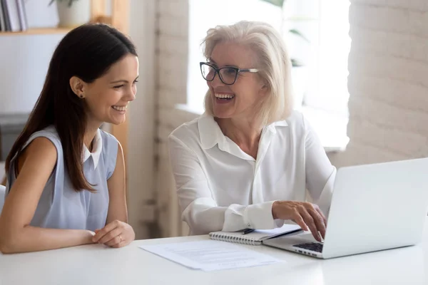 Gelukkige vrouwelijke medewerkers lachen om het bespreken van project op laptop — Stockfoto