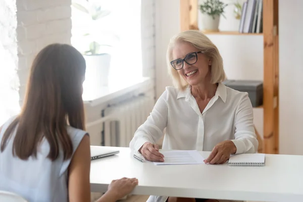 Sonriente mujer de negocios sénior teniendo entrevista con joven solicitante — Foto de Stock