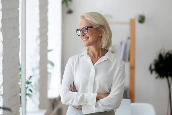 Smiling aged businesswoman look in distance thinking — Stock Photo, Image