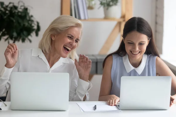 Happy female employee laugh using laptops in office — Stock Photo, Image