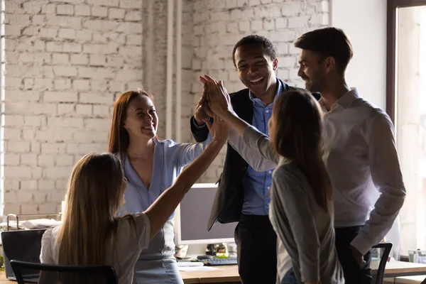 Farklı çalışanlar ekibi yüksek beş veren, iş başarısını kutluyor