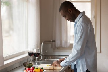 Gülümseyen biracial adam mutfakta romantik akşam yemeği hazırlanıyor