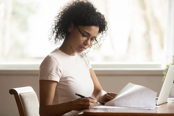 Фокусная женщина в очках изучает правильную бумажную работу. — стоковое фото