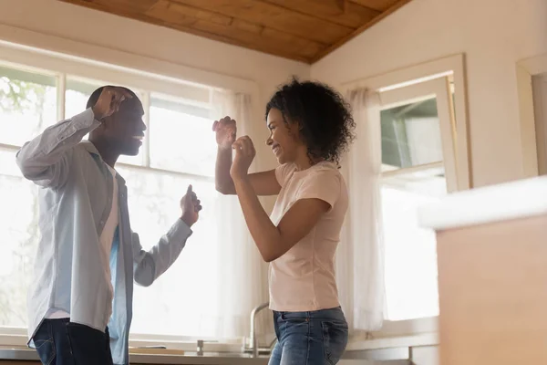 Happy biracial couple dancing in kitchen celebrating relocation — Stock Photo, Image