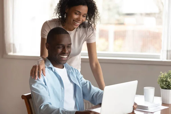 Happy biracial couple look at laptop screen using internet — Stock Photo, Image