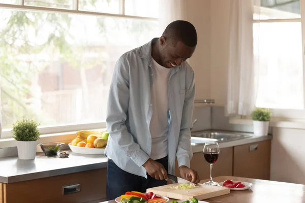 Glimlachend Afro-Amerikaanse man bereidt voedsel in de keuken — Stockfoto