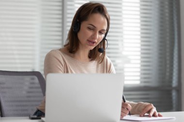 Ciddi genç kadın icra yöneticisi kulaklık takıyor, görüntülü görüşme yapıyor.