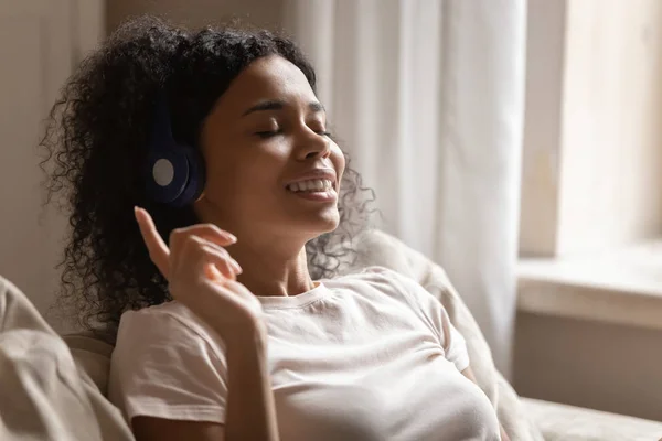 Glücklich biracial Frau in Bluetooth-Kopfhörer entspannen zu Hause — Stockfoto