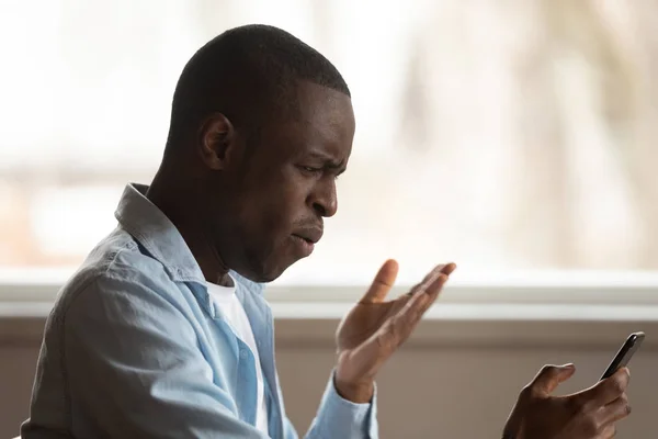 Frustrated biracial male confused by smartphone problems — Stock Photo, Image