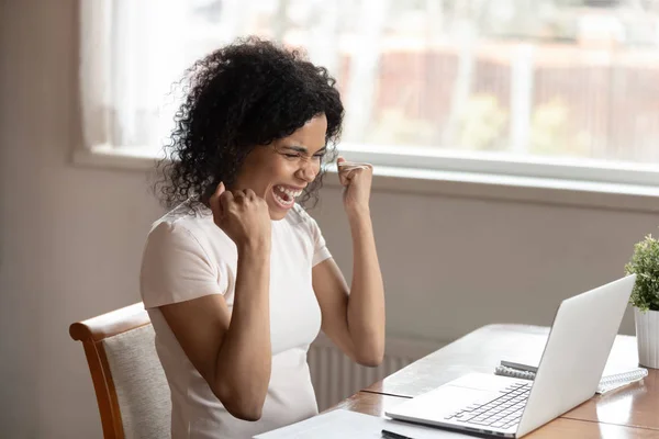 Upphetsad biracial kvinna Triumph läsa nyheter på laptop — Stockfoto