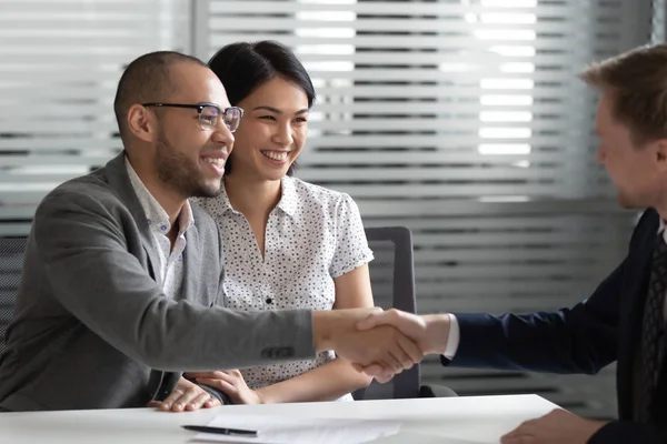 Cheerful mixed race married spouse shaking hands with real estate agent. — Stock Photo, Image