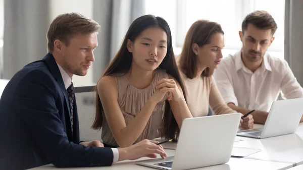 Groupes mixtes d'employés assis à une table commune, travaillant sur différents projets . — Photo