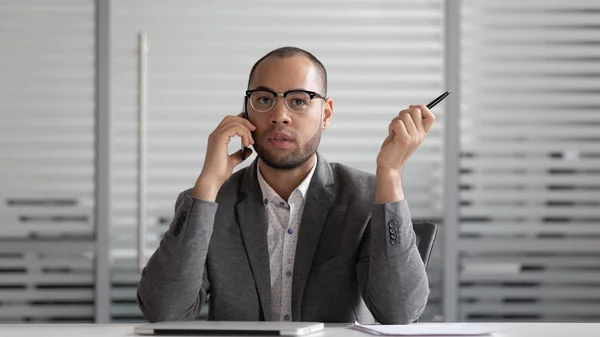Koncentrerad afrikansk amerikansk manlig VD förhandlar på smartphone med klient. — Stockfoto
