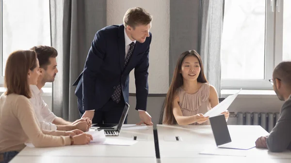 Feliz empleado chino compartir papel buenos resultados financieros con los compañeros de trabajo . — Foto de Stock