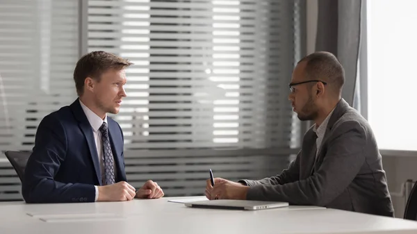 Two multiracial focused male partners discussing company development strategy. — Stock Photo, Image