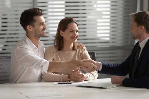 Happy family young couple shaking hands with financial advisor. — Stockfoto